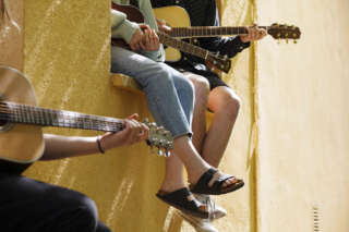 Nuoret soittavat kitaraa ulkona ikkunalaudoilla istuen